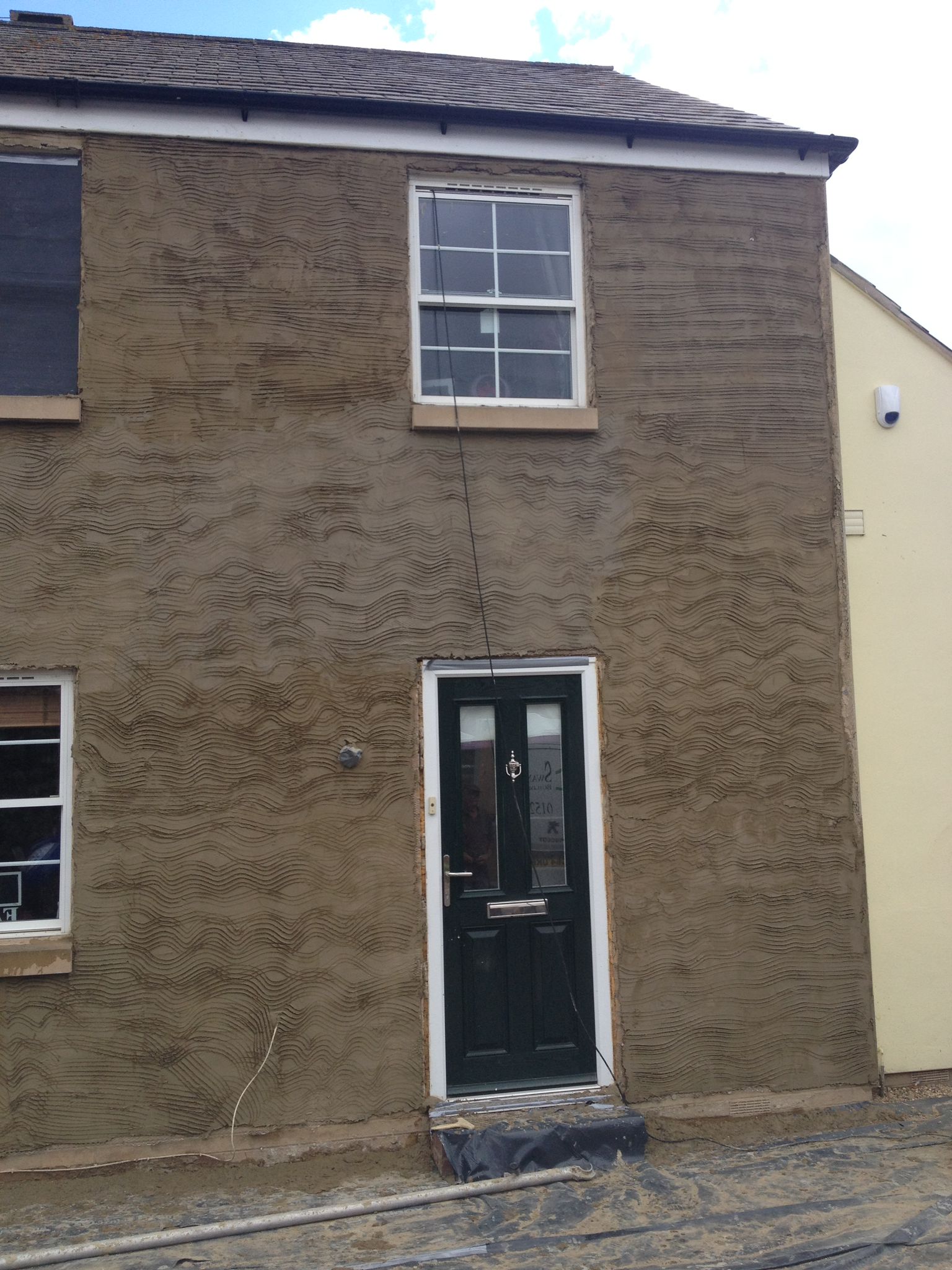 Exterior render scratchcoat applied to a stone house facade by Kat Plastering
